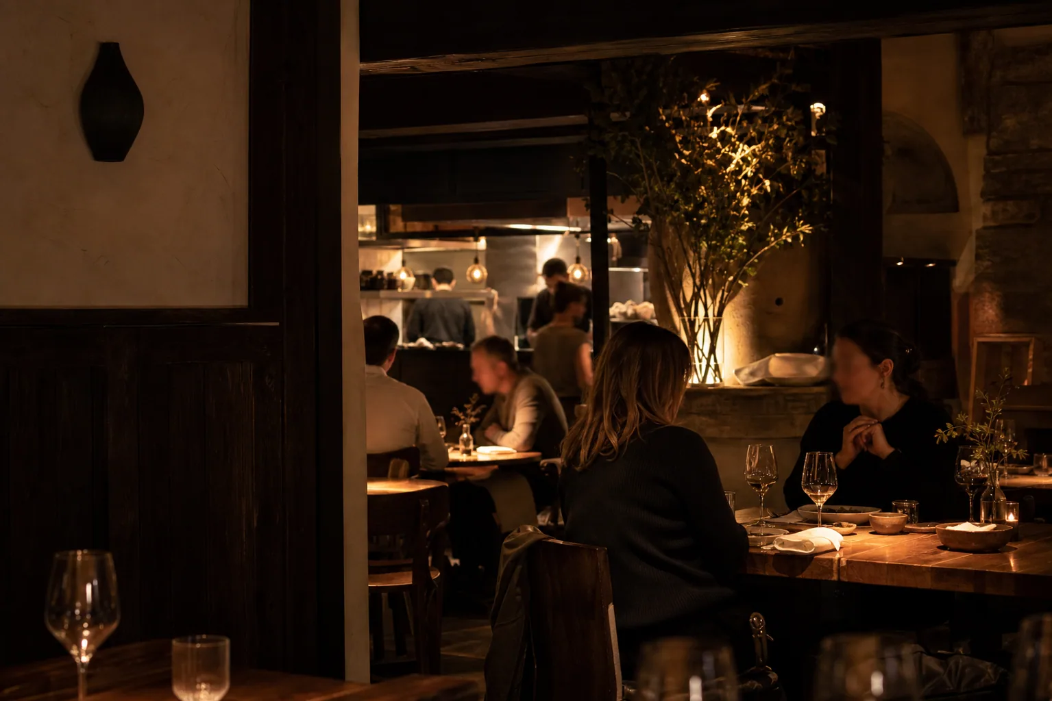 Comedor de Casa Otano con mesas de madera, luz cálida y barra al fondo